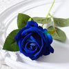A deep blue velvet artificial rose with green leaves on a white plate.