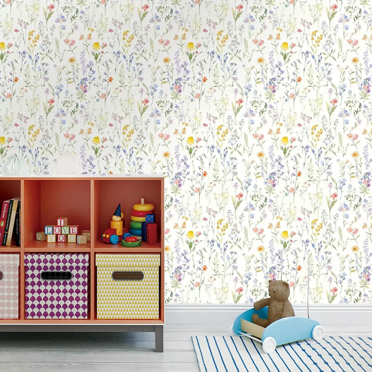 A wooden shelf unit displaying colorful storage boxes against a floral wallpaper background.