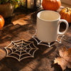 A white mug rests on a wooden spider web ornament on a rustic wooden surface with autumn decor.