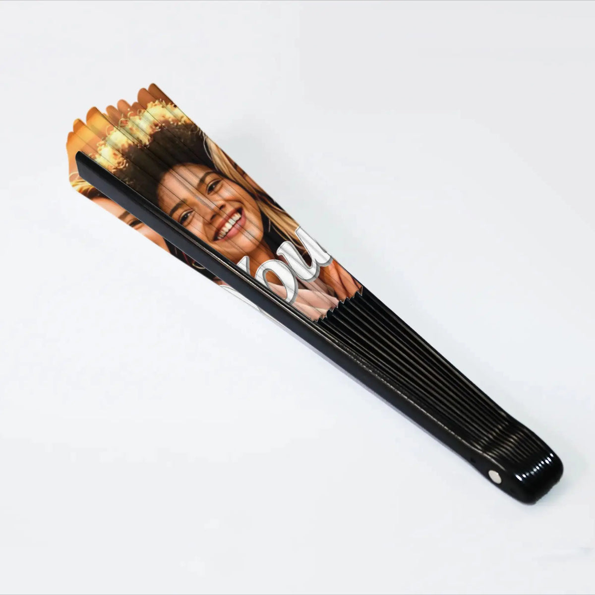 A black folding fan decorated with a custom photo of a smiling woman's face.