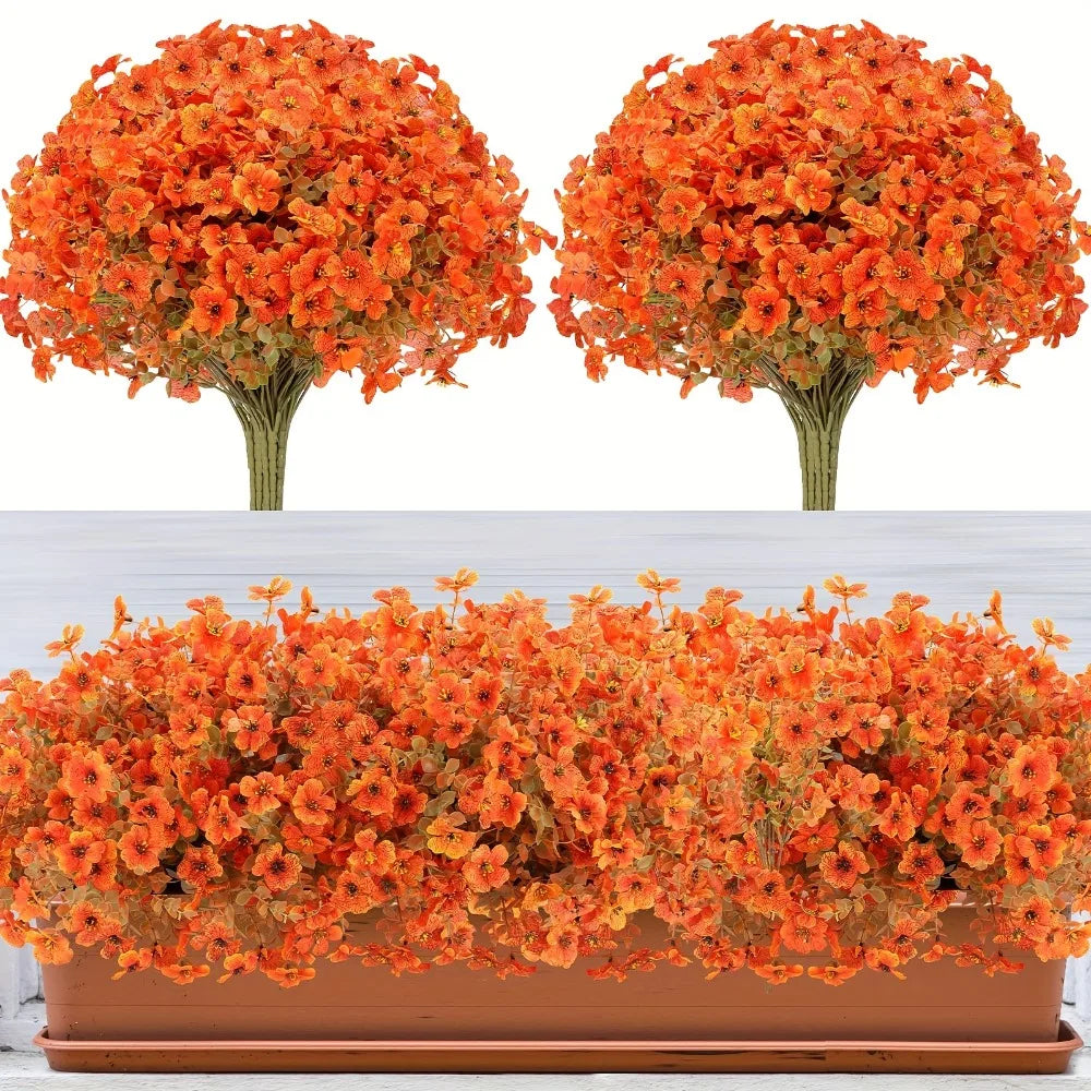 Two artificial orange fall floral trees displayed next to a potted arrangement of orange and yellow flowers.