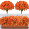 Two artificial orange fall floral trees displayed next to a potted arrangement of orange and yellow flowers.