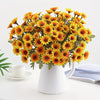 A bouquet of bright orange and yellow silk gerbera daisy artificial flowers in a white ceramic vase.