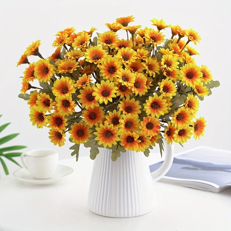 A bouquet of bright orange and yellow silk gerbera daisy artificial flowers in a white ceramic vase.
