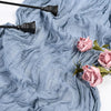 Light blue cheesecloth table runner draped with pink roses and black decorative elements.