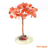 A natural crystal money tree decor featuring reddish-orange translucent beads on a copper wire stem and a light green base.