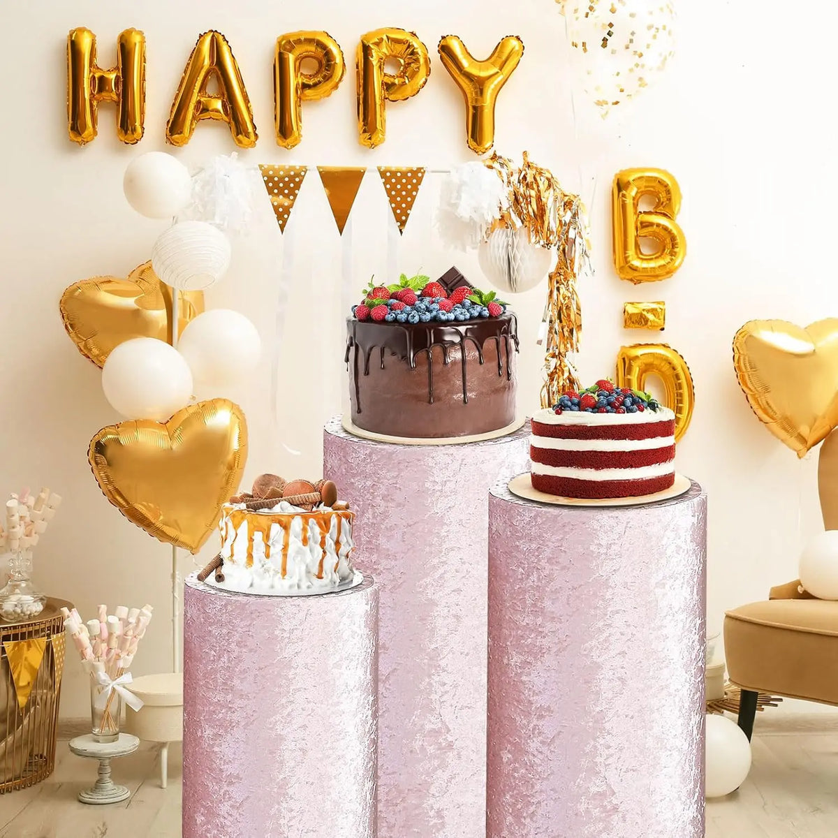Pink spandex cylinder stand covers decorated with gold balloons and confetti for a party display