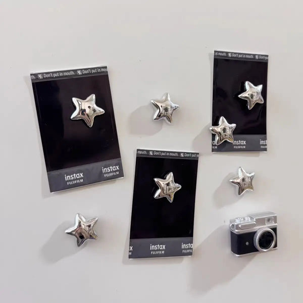A collection of black Instax film cartridges featuring a 3D shiny star design for fridge magnets.