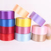 A collection of rolled satin ribbon in various colors including purple, blue, red, yellow, and pink.