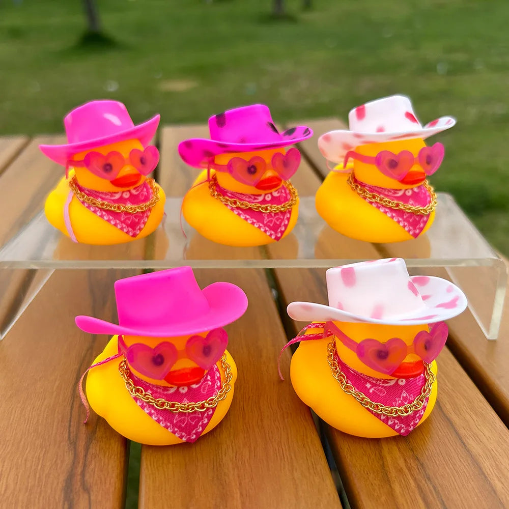 Three rubber duck car dashboard decorations featuring pink cowboy hats and yellow bodies with pink and gold accents.