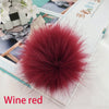 Pompon accessoire en fausse fourrure rouge vin resting sur un livre.