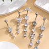 A set of five gold tone butterfly and flower belly rings displayed on a light beige surface.