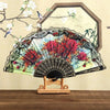 A Spanish style folding lace trim handheld fan with a colorful floral pattern displayed against a light background.