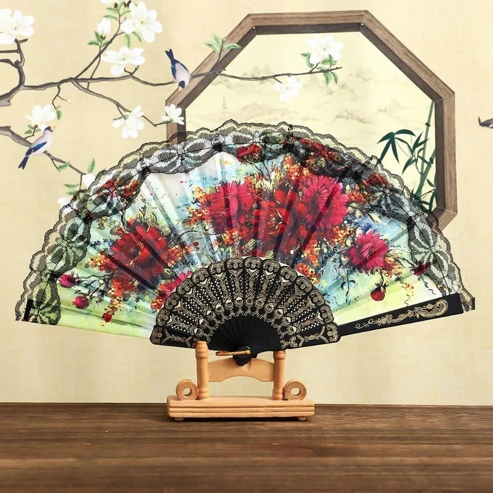 A Spanish style folding lace trim handheld fan with a colorful floral pattern displayed against a light background.