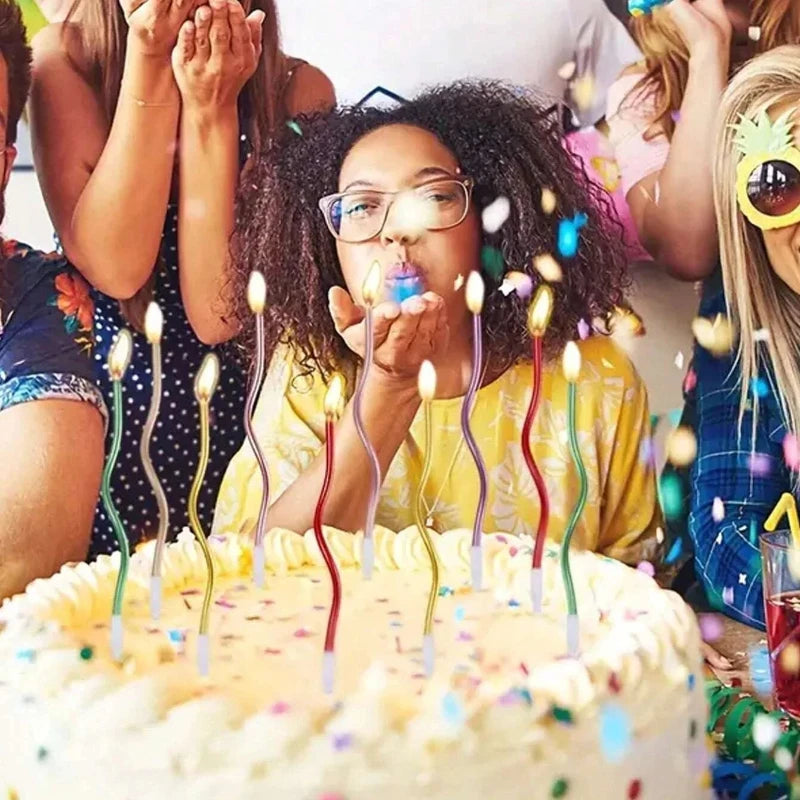 A person is blowing out candles on a birthday cake with many colorful lights and confetti in the background.