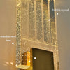 Close-up of a modern wall sconce featuring a stainless steel base and vertical glass panels with embedded bubble crystals.