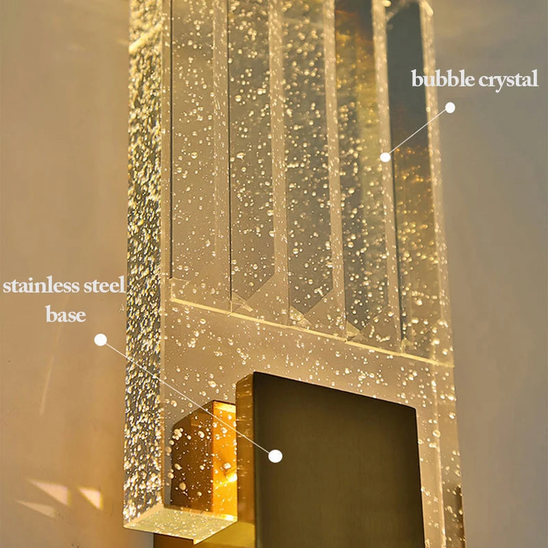 Close-up of a modern wall sconce featuring a stainless steel base and vertical glass panels with embedded bubble crystals.