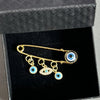 Elegant gold and silver evil eye brooch pin featuring multiple blue and gold eyes