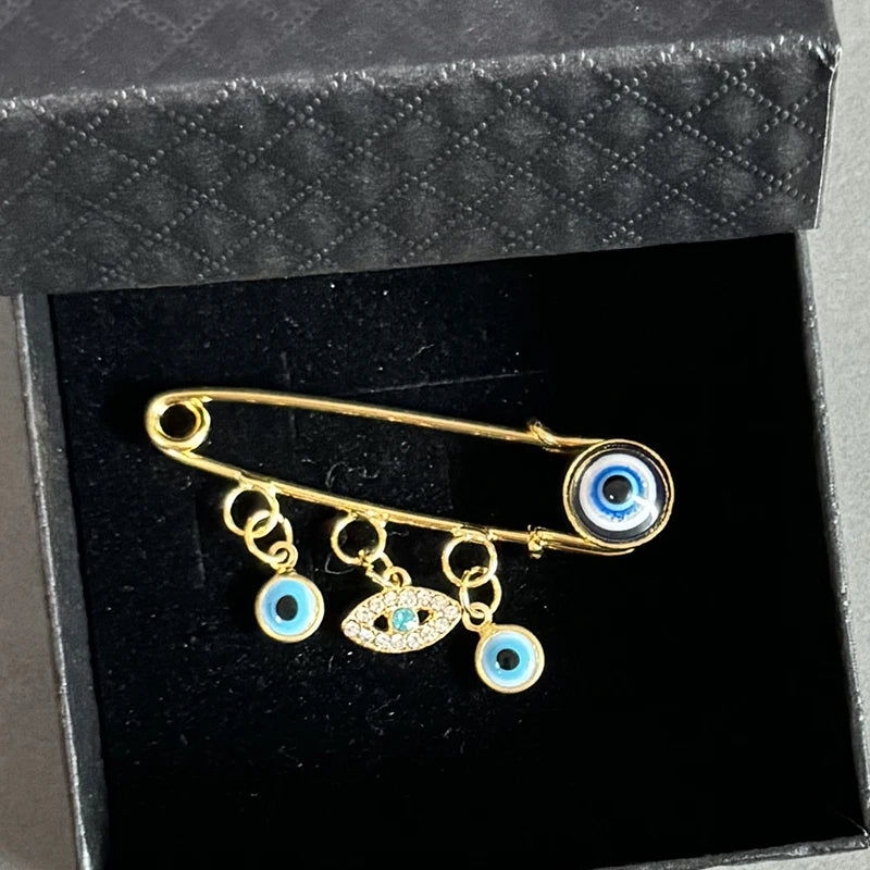 Elegant gold and silver evil eye brooch pin featuring multiple blue and gold eyes
