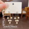 A pair of silver needle pearl tassel earrings are shown against a white background with a measurement guide.