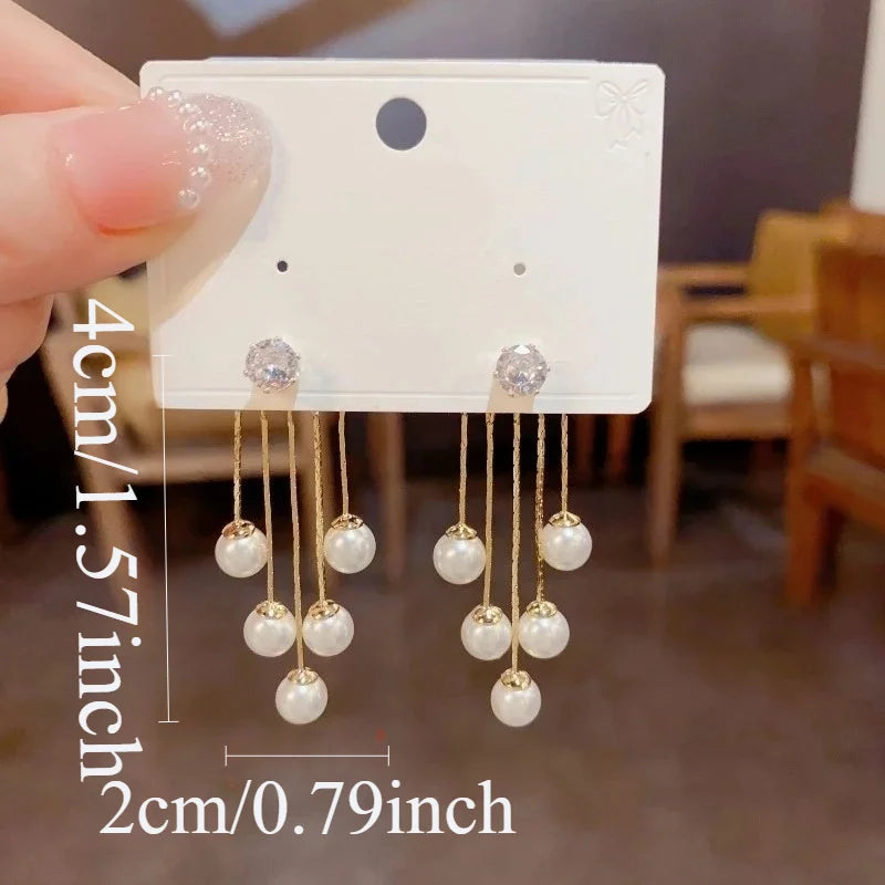 A pair of silver needle pearl tassel earrings are shown against a white background with a measurement guide.