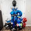 A balloon bouquet featuring silver, blue, and black foil balloons shaped like the number 2 and various other shapes for a par