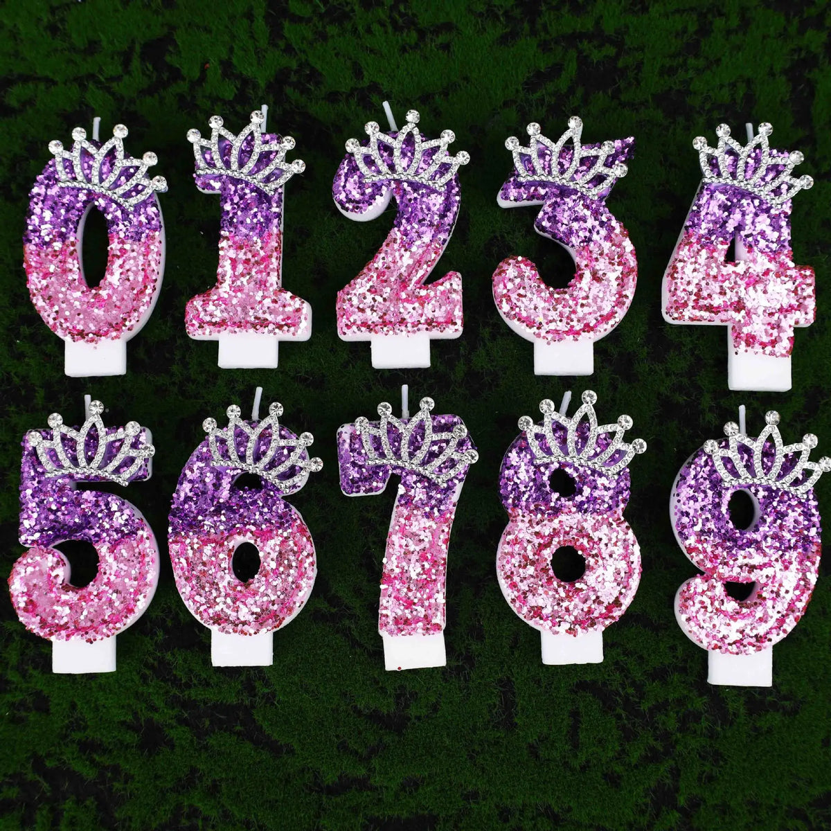 A set of glitter number birthday candles with rhinestone crown toppers in various shades of purple and pink.