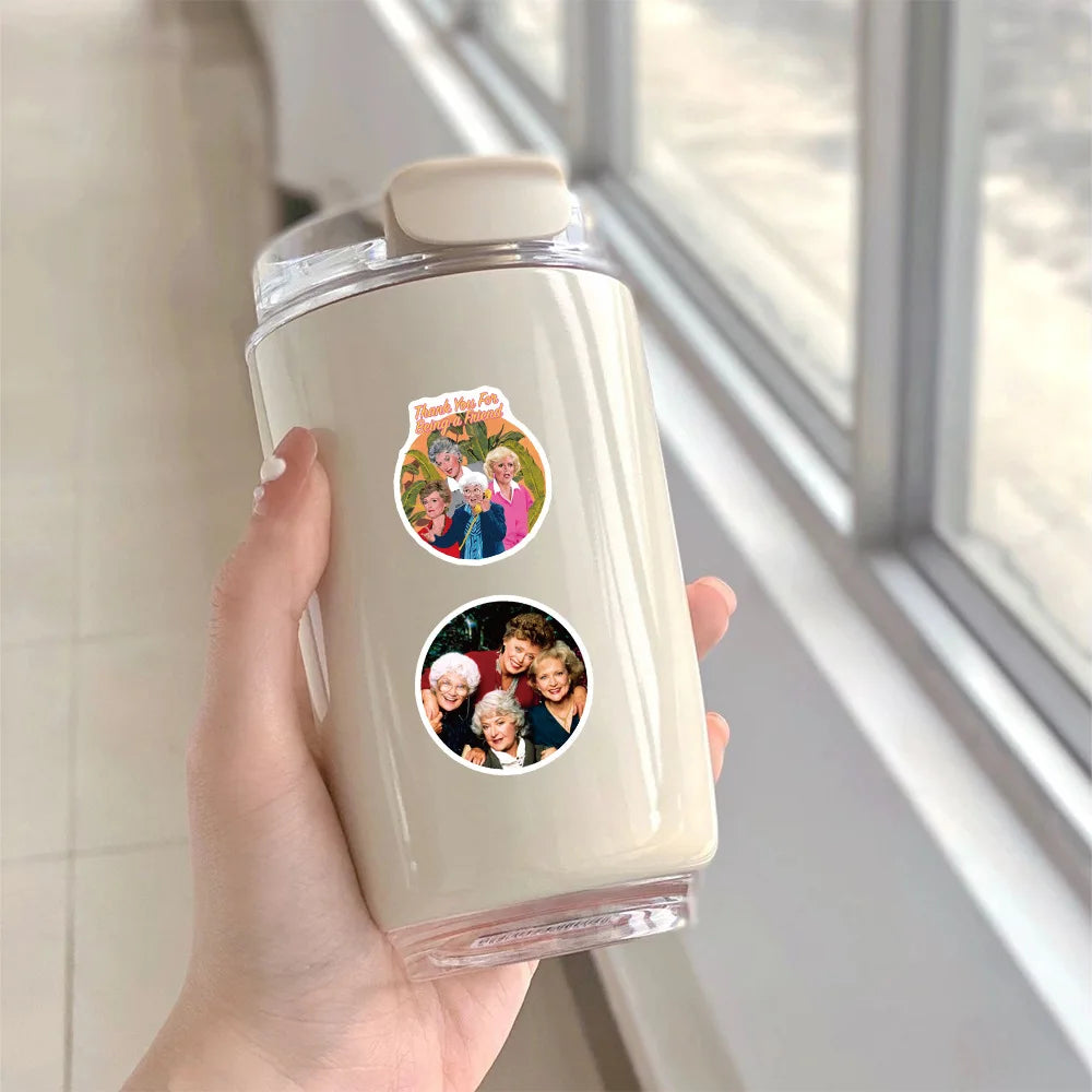 A hand holds a clear plastic bottle containing a sticker pack featuring the Golden Girls characters for DIY decoration.