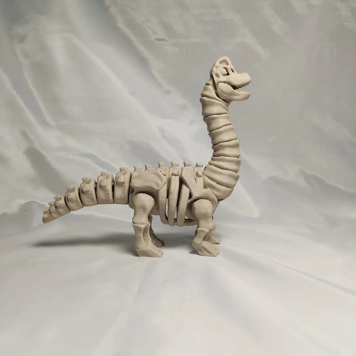 A light beige 3D printed dinosaur skeleton figurine featuring a T-Rex and Mosasaurus.