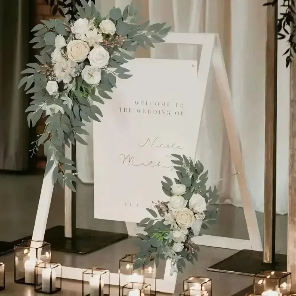 A wedding arch display featuring white and dusty rose flowers and silvery-green eucalyptus greenery.