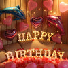 A birthday display featuring pink and purple heart-shaped balloons and warm white LED alphabet letters.