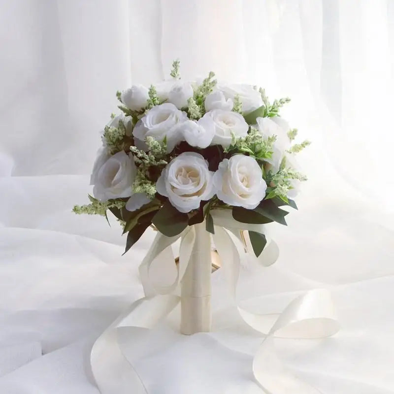 Elegant white silk rose bridal bouquet with green foliage tied with a sheer ribbon