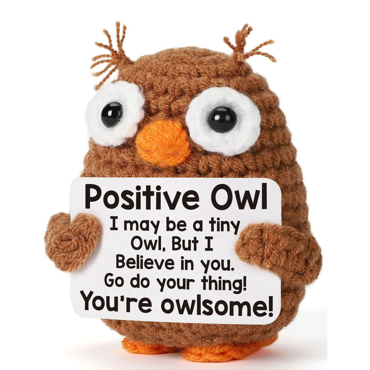 A handmade crochet owl doll with large eyes and brown fur holding an inspirational card