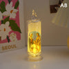 A clear glass flameless LED religious prayer candle with a golden glow and a small flame-like top.