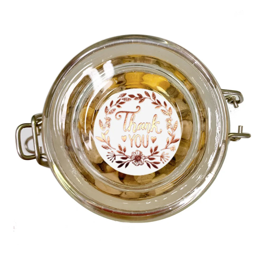 Round gold foil thank you sealing stickers in a glass jar for gifts and packaging