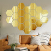 A piece of gold-toned hexagon mirror wall decor stickers mounted on a light gray wall.