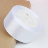 A roll of white satin ribbon for crafts and gift wrapping resting on brown kraft paper.