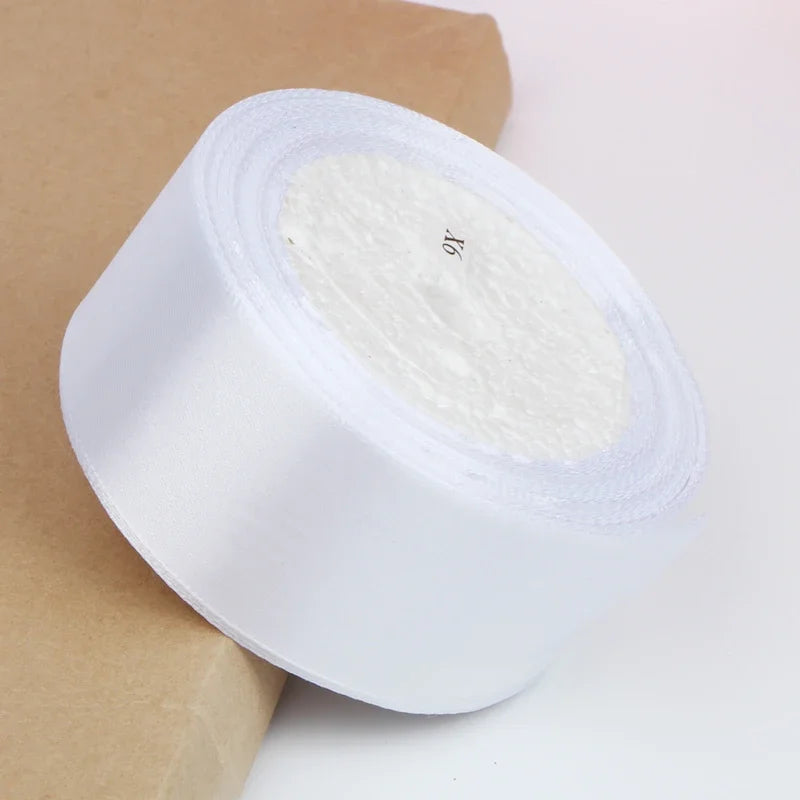 A roll of white satin ribbon for crafts and gift wrapping resting on brown kraft paper.
