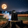 A black ghost figurine with glowing eyes sits on a tree stump under a bright moonlit night sky.