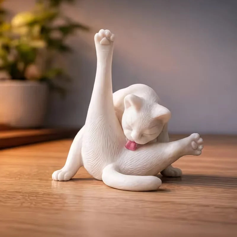 Figura de gato impresa en 3D de color blanco con una pata levantada, sentada sobre una superficie de madera.