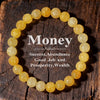 A bracelet made of small, round yellow citrine crystals is laid on a dark wooden surface.