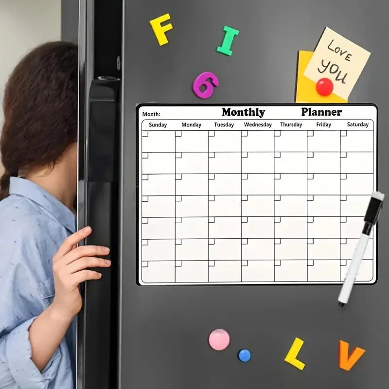 A magnetic dry erase monthly planner calendar is displayed on a refrigerator door with colorful markers.