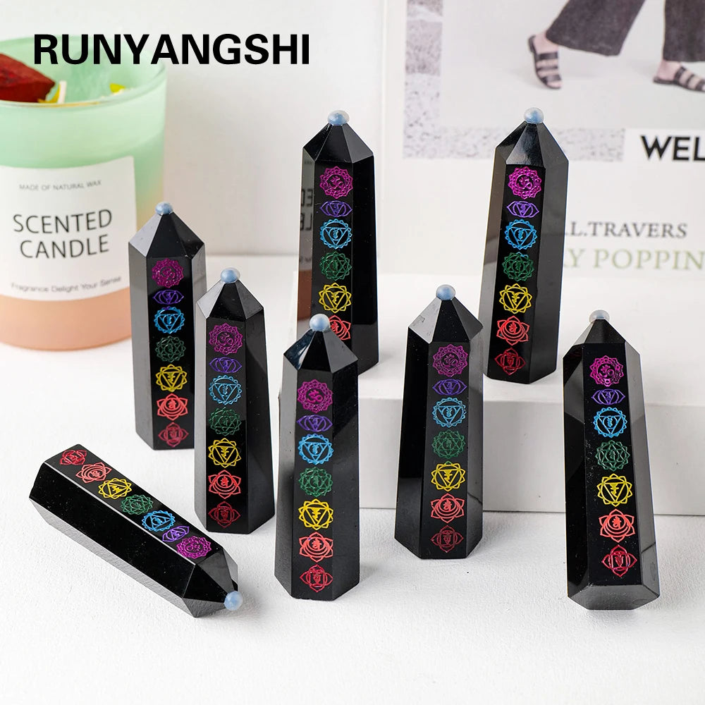 A collection of black obsidian crystal towers with colorful gemstone carvings displayed on a white surface.