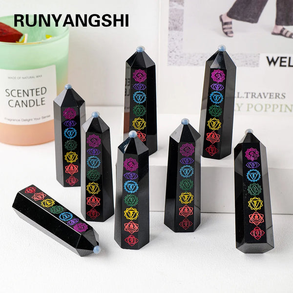 A collection of black obsidian crystal towers with colorful gemstone carvings displayed on a white surface.
