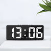 A black digital alarm clock displaying the time 13:06 on a white surface.