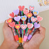 A hand holds a cluster of heart-shaped multicolor ballpoint pens for Valentine's Day