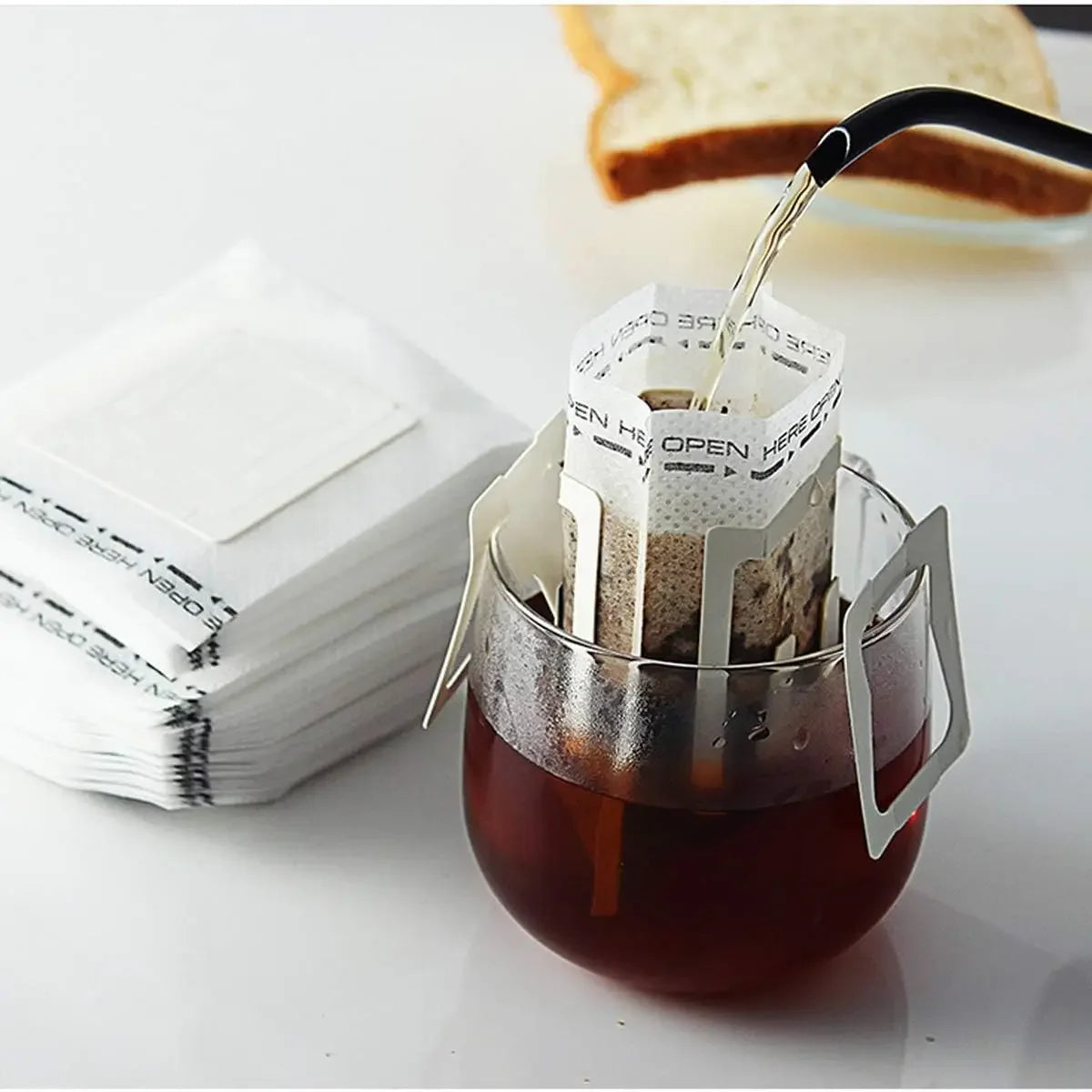 A black coffee filter is being poured into a glass of brewed coffee, next to a stack of white disposable filters.