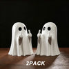 A pair of white glow-in-the-dark ghost figurines with playful poses displayed on a dark surface.