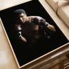 A portrait of a boxer in boxing gloves against a dark background, displayed in a framed poster.
