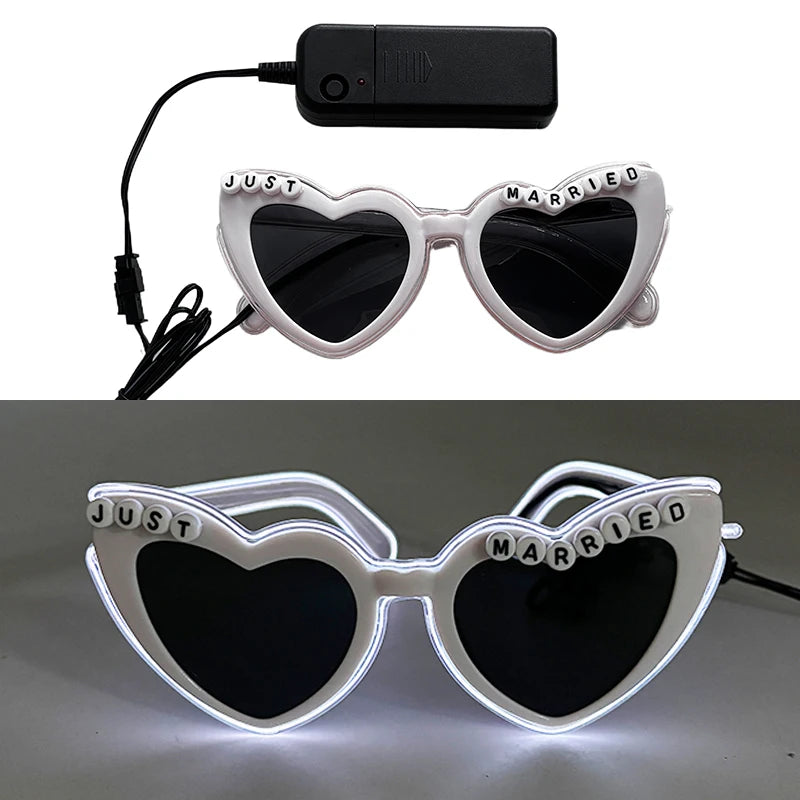 Pair of white heart-shaped sunglasses with 'just married' text and LED lights on a black strap
